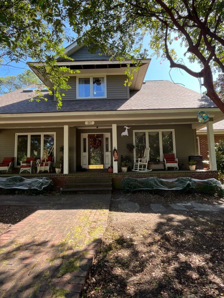 Charming home exterior with modern windows, inviting porch seating, and seasonal decor, showcasing energy-efficient upgrades and enhanced curb appeal.